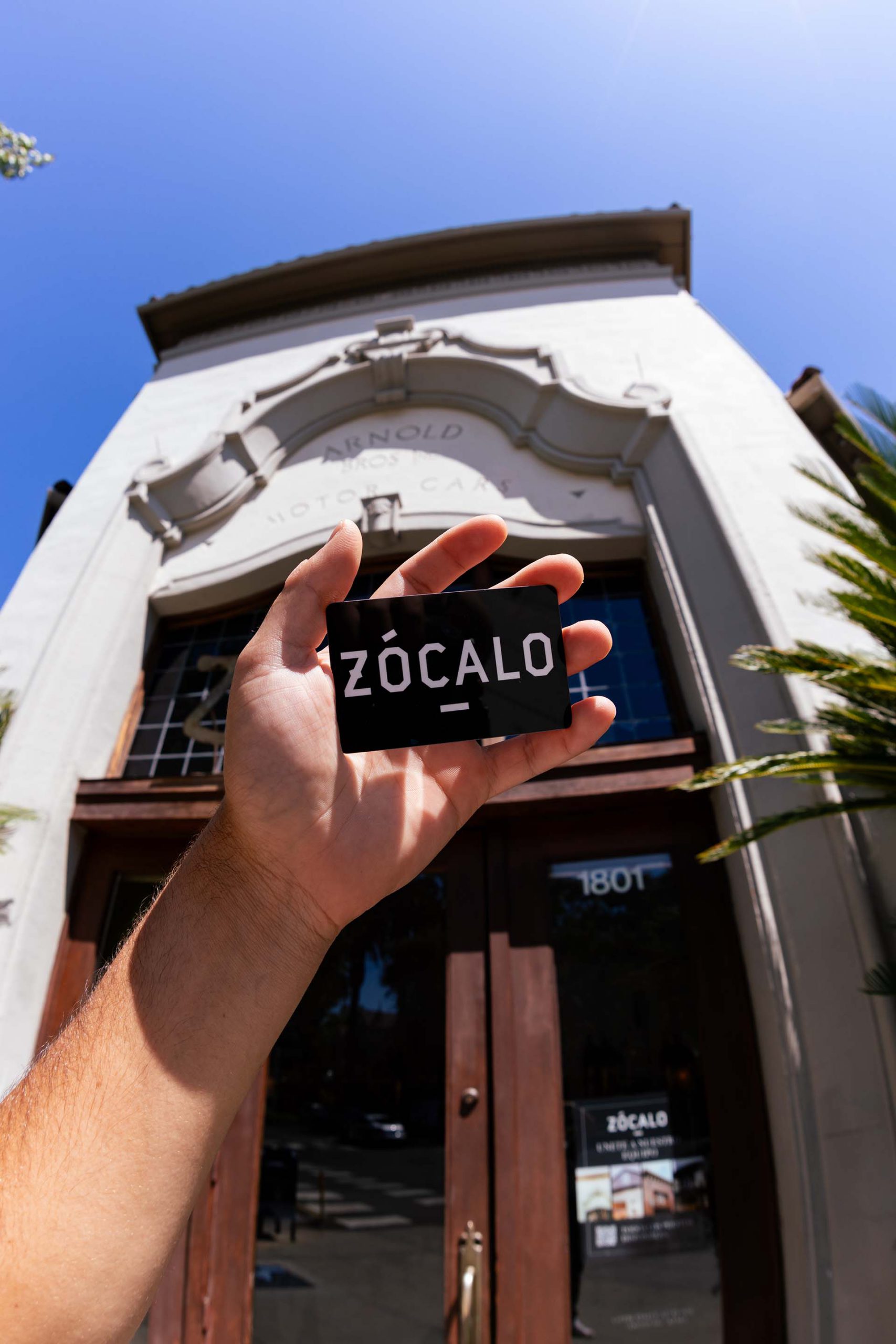 Man holding a Zocalo gift card in front of restaurant